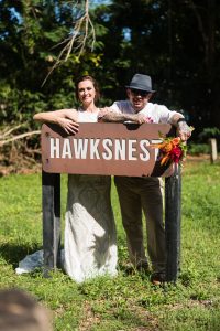 a bride and groom by the sign at hawksnest beach on st john
